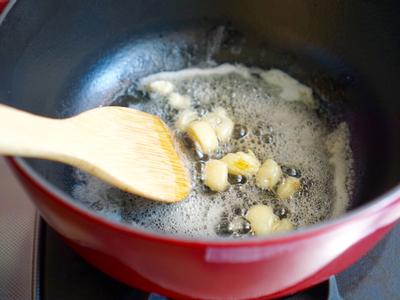 鑄鐵鍋開小火熱鍋，放下奶油與切過的蒜頭煎到微焦。