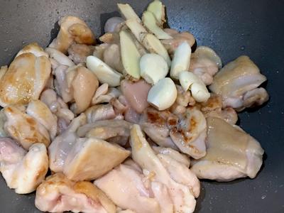 加入雞肉翻炒上色，然後下蒜頭及薑片拌炒。